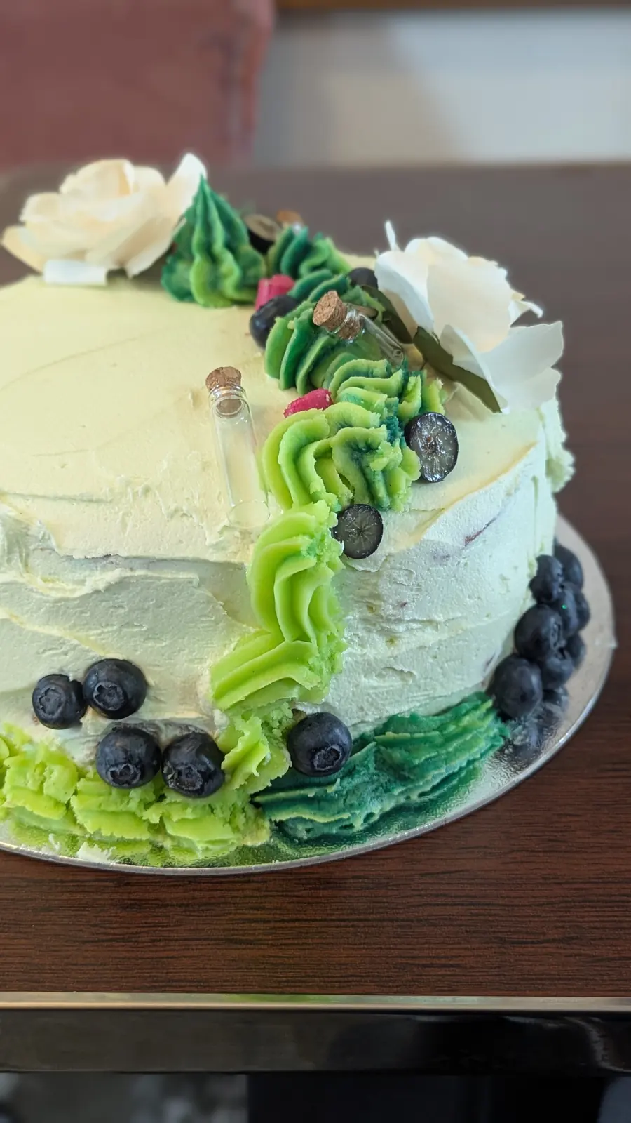 A green celebration cake with berries and cream.