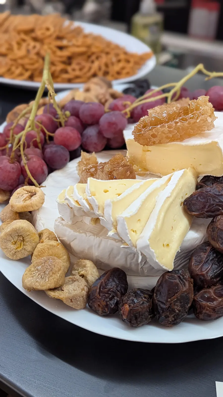 A cheese board with grapes, figs and crackers