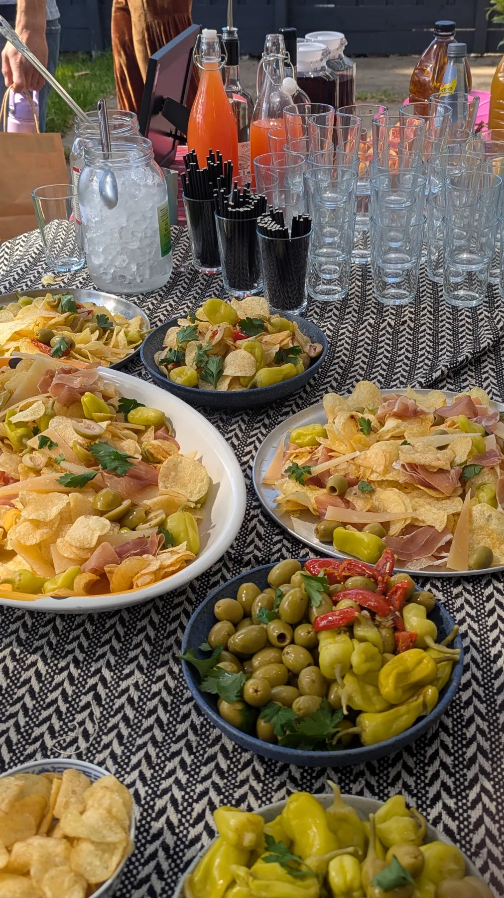 An outdoor table of shared plates and drinks.